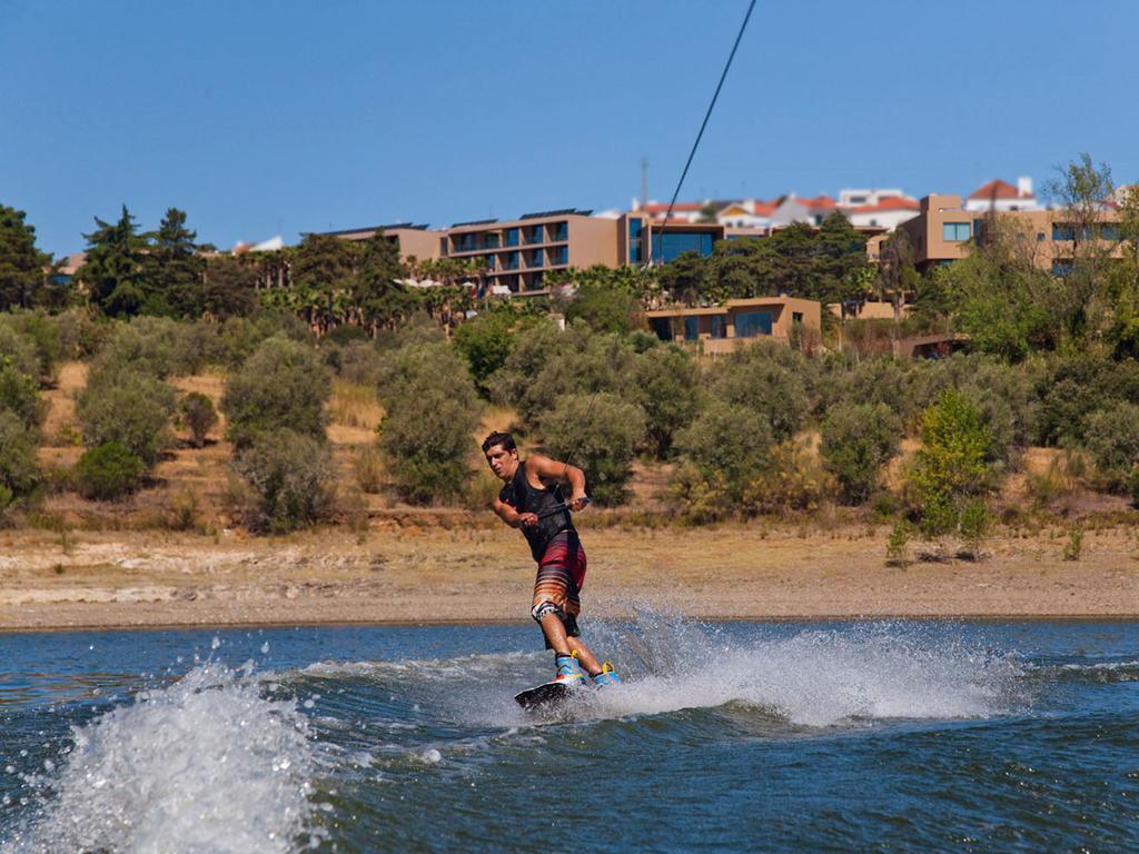 Ap Lago Montargil - Conference & Spa Ngoại thất bức ảnh The photo shows a person wakeboarding on a body of water. The individual is being pulled by a cable, which is likely connected to a boat or a winch. The person is wearing a life jacket and swim shorts, balancing on the board as they enjoy the activit