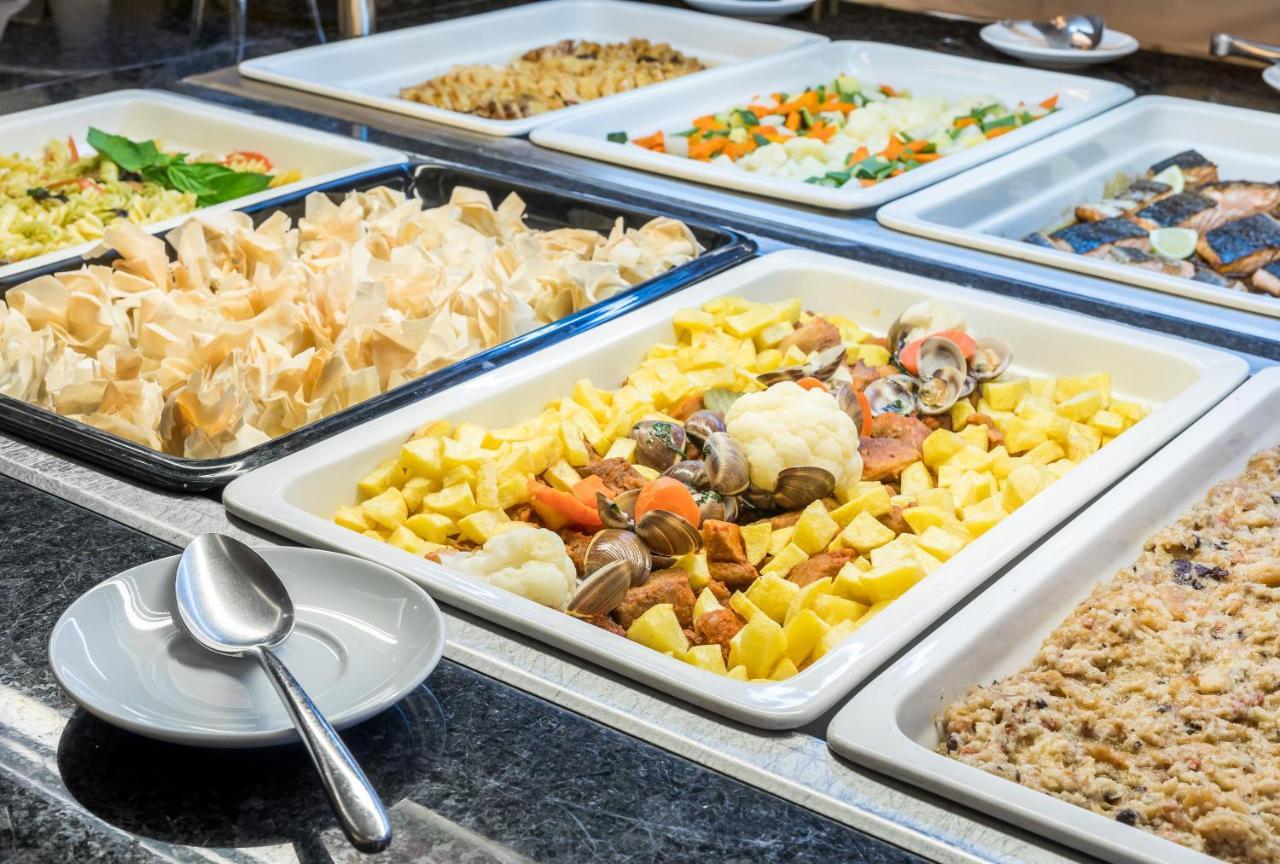 Ap Lago Montargil - Conference & Spa Ngoại thất bức ảnh The photo shows a buffet-style display of various dishes. There are several rectangular trays filled with different types of food. 

1. One tray contains a mix of vegetables and seafood, likely including potatoes and cauliflower.
2. Another tray hold