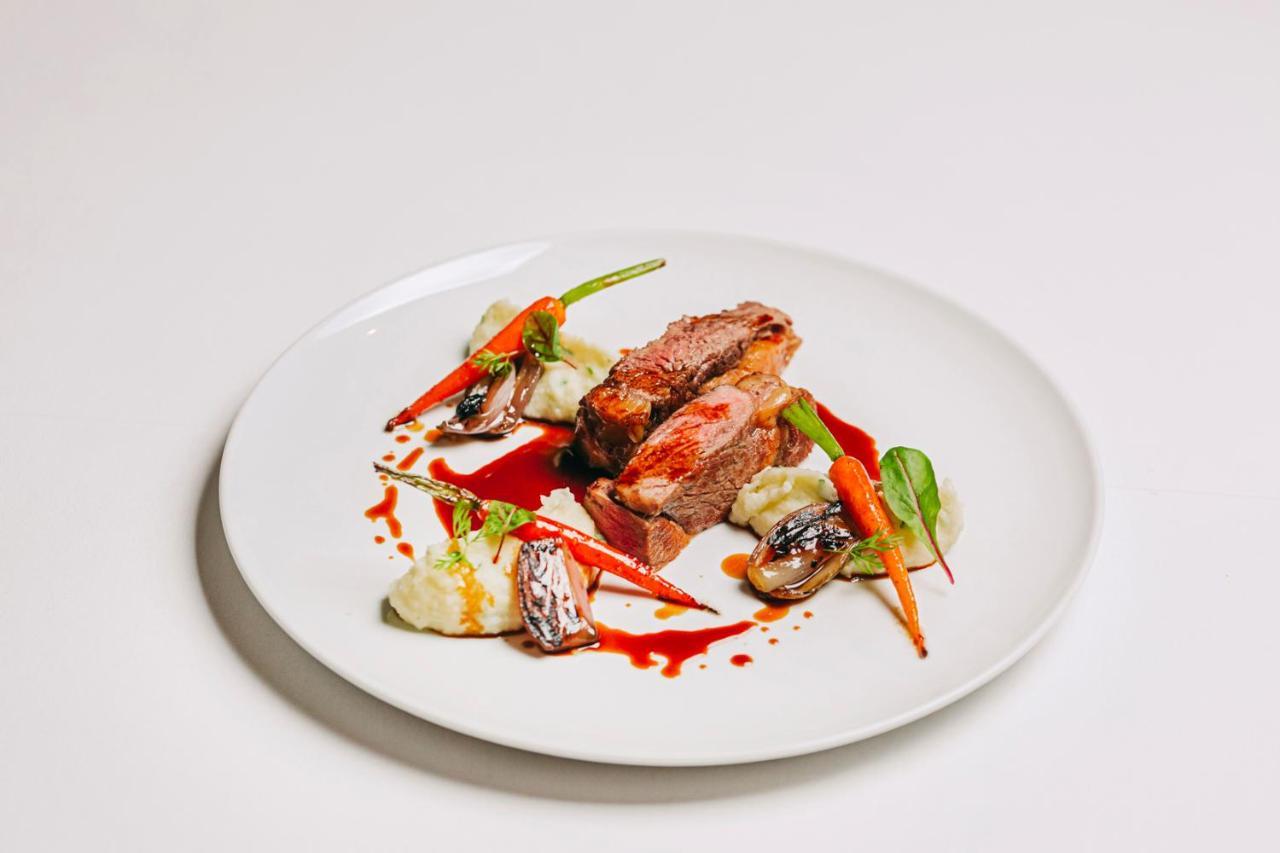 Ap Lago Montargil - Conference & Spa Ngoại thất bức ảnh The photo features a beautifully plated dish. At the center, there are slices of a tender meat, likely beef, showcasing a juicy pink interior. Accompanying the meat are several elements: vibrant orange carrots, perhaps roasted or glazed, and dollops 