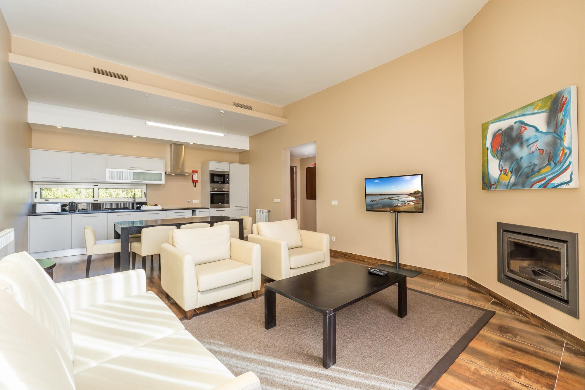 Ap Lago Montargil - Conference & Spa Ngoại thất bức ảnh The photo shows a modern, spacious living area with a contemporary design. The room features light-colored walls and wooden flooring. 

In the center, there is a black coffee table surrounded by four white armchairs. A flat-screen TV is mounted on th